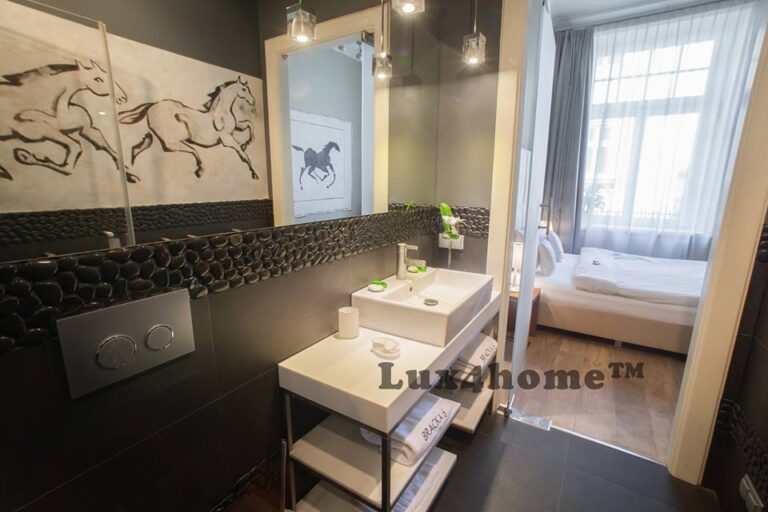 Kamień w hotelowych łazienkach w Krakowie — otoczaki i umywalki 3 Pas czarnej mozaiki otoczakowej nad białymi umywalkami w łazience