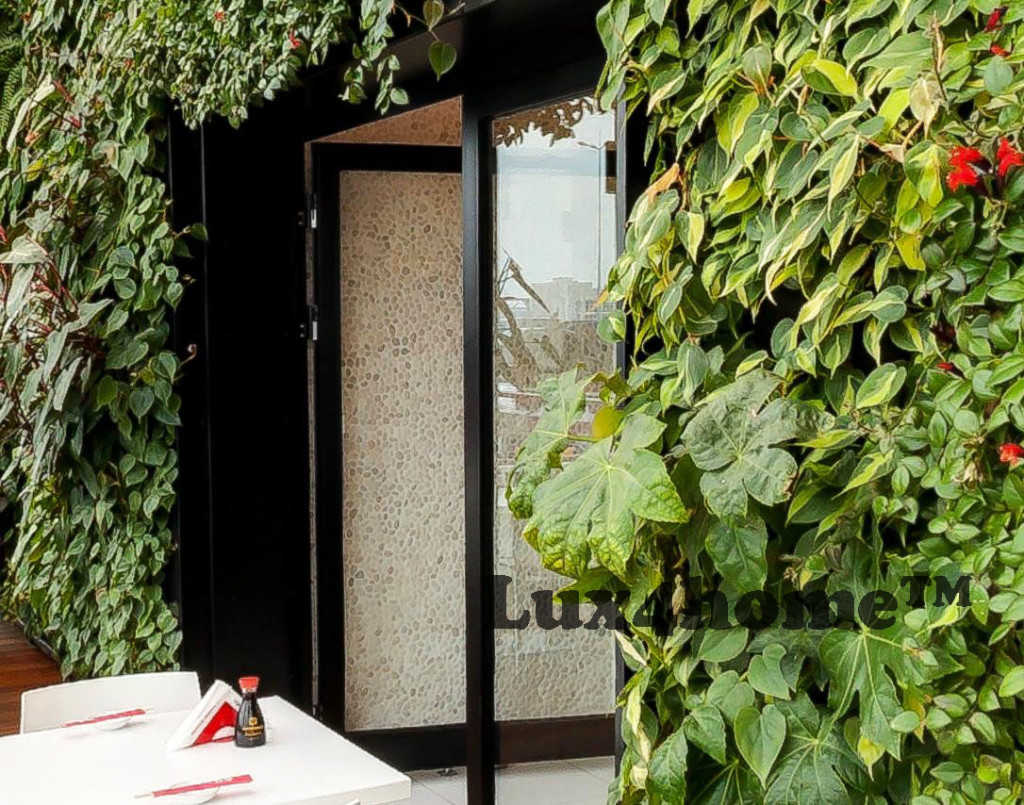 Białe otoczaki na ścianach — realizacja Tokyo Sushi w Warszawie 35 Zielona ściana roślinna obok drzwi z okładziną z otoczaków WHITE TIMOR